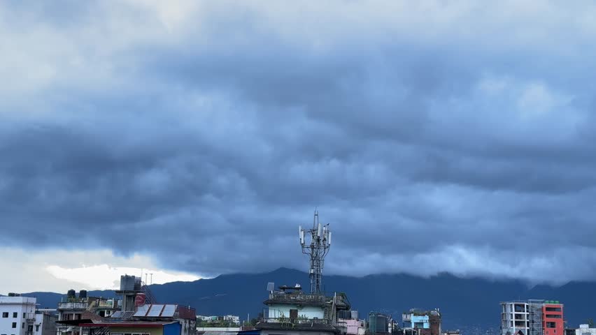 panoramic view of dense clouds looming over the city of kathmandu before rain,with a mobile tower on a rooftop among the bustling urban landscape. perfect for weather and urban themes.