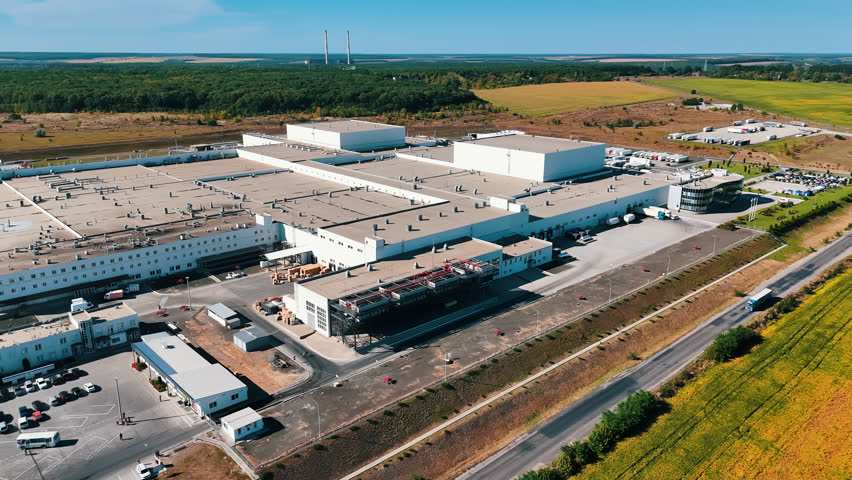 Flight around the large industrial enterprise on sunny daytime. Aerial perspective on the modern plant in the countryside.