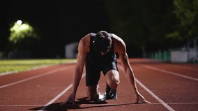 Strong Young Man Starting a Race From Track Starting Blocks Position on a Dark Stadium in the Evening. Cinematic Portrait of a Fit Male Sprint Runner Participating in a Competition - Powered by Shutterstock - Get 15% off with code: PIKWIZARD15