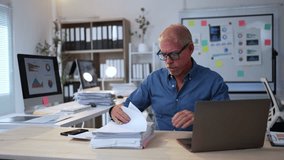 Accountant sitting at a desk, reviewing documents and analyzing data in a busy office environment - Powered by Shutterstock - Get 15% off with code: PIKWIZARD15