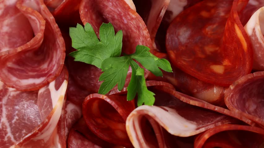 Charcuterie board with various cured meats and sausages circle rotation close up top view