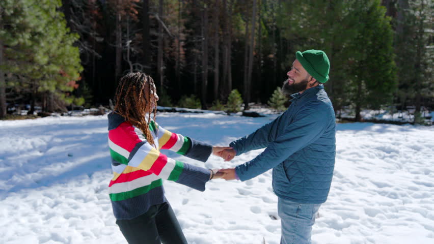 Joyful African American couple savoring a delightful winter day together in the breathtaking Yosemite National Park, enveloped by pristine snow and stunning natural scenery that surrounds them