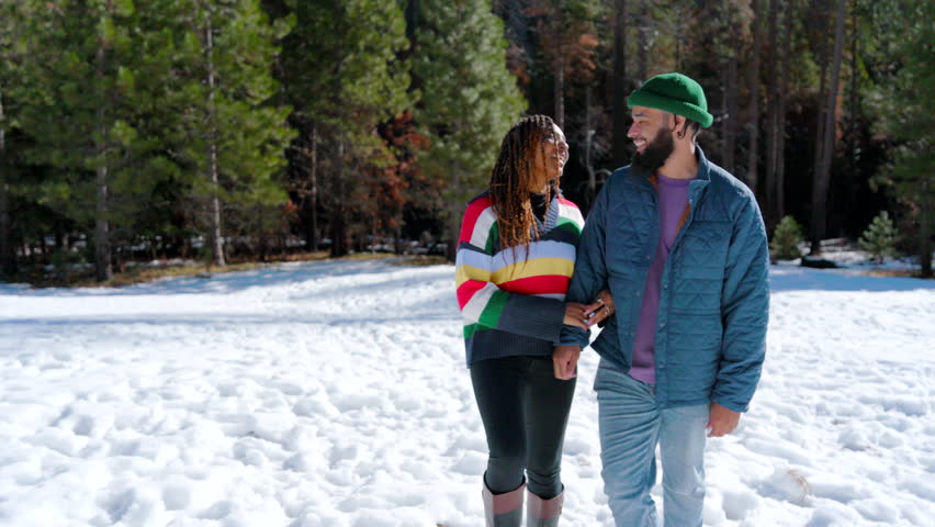 A loving couple, deeply engaged in their affection, enjoys a romantic walk through the snowy landscape of Yosemite National Park, highlighting their bond and the beauty of nature in winter