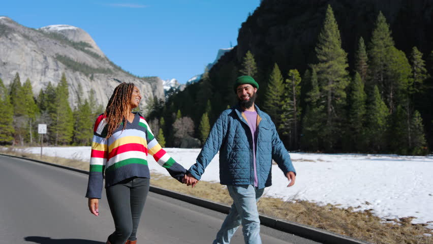 A lovely couple enjoys a warm winter day in Yosemite National Park, walking handinhand through stunning landscapes of sparkling snow and towering trees that enhance their unforgettable experience