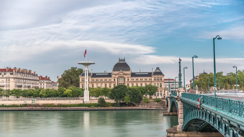Panoramic hyperlapse view of the Rhone River and its embankment, featuring the University Jean-Moulin in Lyon, France. Includes the University Bridge and waterfront under a partly cloudy sky timelapse