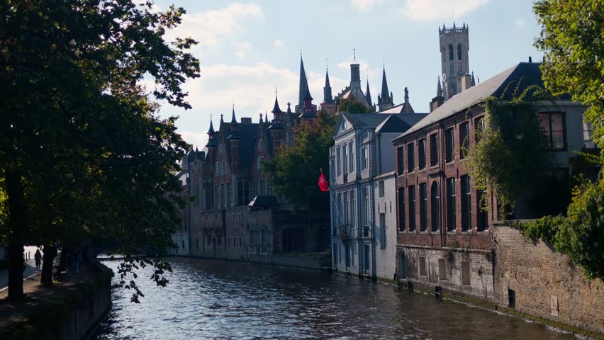 Historic canal view in Bruges with medieval buildings and autumn foliage on a sunny day