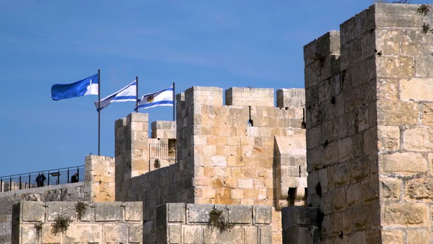 Three flags flying over stone walls at Jaffa Gate in Old Town Jerusalem