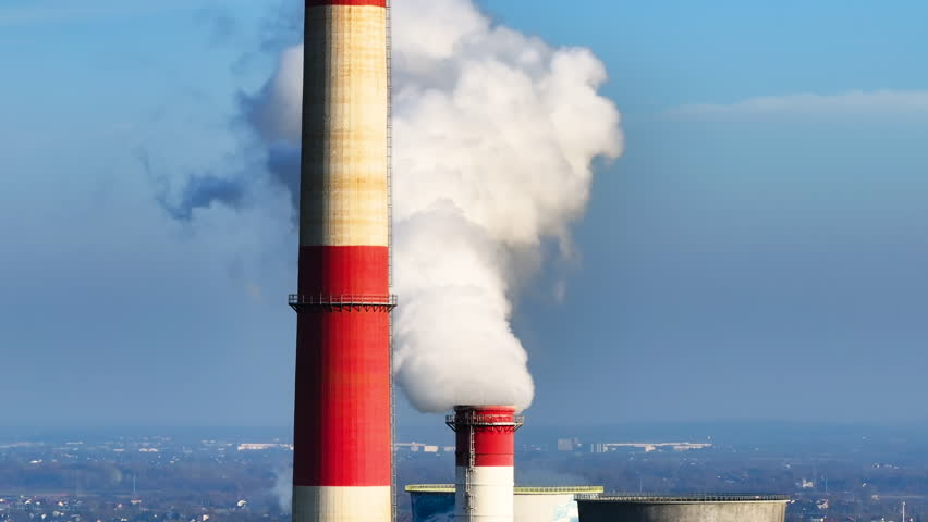 Power plant emissions rise into the sky over a landscape, showcasing industrial activity and environmental impact