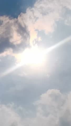 Timelapse moving clouds in the blue sky covering the sun on vertical footage video. Clouds moves in blue sky at day. Natural cloudscapes background. 4k footage cloudy sky with sun rays in summer.