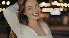 A close-up of a happy woman smiling at night, with a beautiful bokeh background of lights. Happy Woman Smiling at Night with Beautiful Bokeh Background. Beautiful Woman Posing - Powered by Shutterstock - Get 15% off with code: PIKWIZARD15
