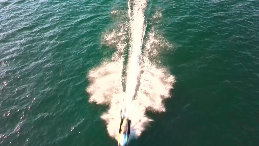 Man riding jetski cinematic aerial chase footage, beautiful Lake George NY backdrop, 4k drone footage, minimal color grade. 