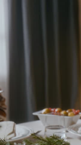 Vertical close up shot of hands of unrecognizable family members clinking glasses of sparkling wine in toast at Christmas dinner table