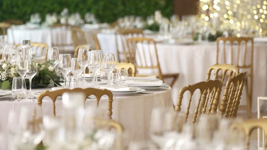 Luxurious wedding table setting with golden chairs, glassware, and floral centerpieces