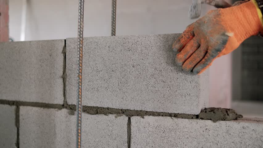 Construction worker laying concrete blocks using mortar of cement and hammer 