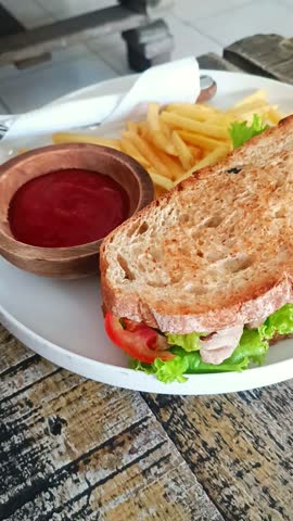 Toasted sandwich with lettuce and tuna on a white plate. Delicious meal with french fries and ketchup