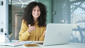 Young adult businesswoman talking on a video call using laptop sitting at workplace in business office. A female manager has a remote business meeting. Coach speaks at an online course or training - Powered by Shutterstock - Get 15% off with code: PIKWIZARD15