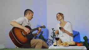 Man plays guitar for young woman on date, birthday, anniversary. Romantic atmosphere, flirting, man impresses woman, plays serenade music. Anniversary, birthday celebration. Concept of love, passion. - Powered by Shutterstock - Get 15% off with code: PIKWIZARD15