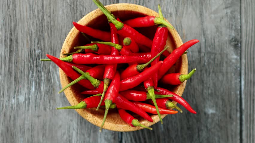 Top-down View Of A Bowl Filled With Vibrant Chili Peppers, Rotating Smoothly To Showcase Their Bright Colors And Glossy Texture In Stunning 4k Resolution. Perfect For Culinary And Spice Visuals.