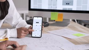 UX UI designer testing prototype on a phone, discussing and brainstorming on wireframes for a website and mobile app prototype, in the concept of website and mobile application design concept. - Powered by Shutterstock - Get 15% off with code: PIKWIZARD15