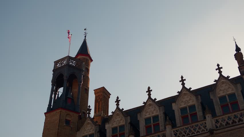 Historic Belgian building with ornate gothic architecture and a tall tower under clear skies