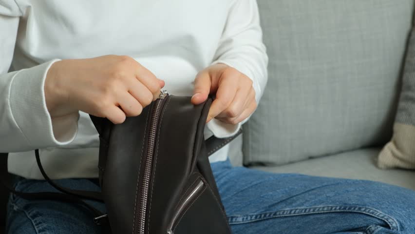 The process of unzipping and fastening a metal zipper on a leather backpack slow motion.