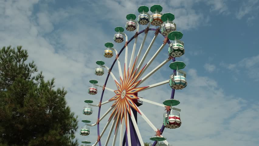 An old Ferris wheel with colorful cabins and green umbrellas in the center of Bukhara