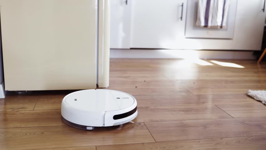 Vacuum Robot cleaning at home. Robot vacuum cleaner in the kitchen. Smart cleaning technology.