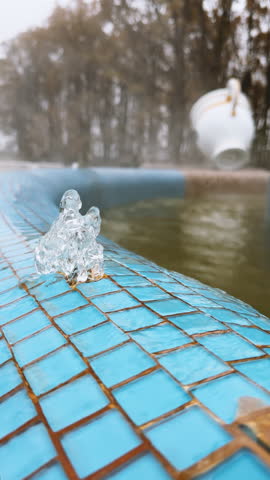 Vertical footage of hot thermal water gushing from a spring and flowing down blue tiles into a pool, creating a pleasant steam around a thermal spa. Spa, wellness, relaxation concept. Thermal baths