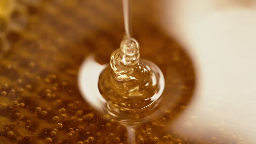 Honey dripping from honeycombs extreme macro. Natural bees wax cells, gold nectar. Pure golden elixir. Amazing tasty flow. Yellow background