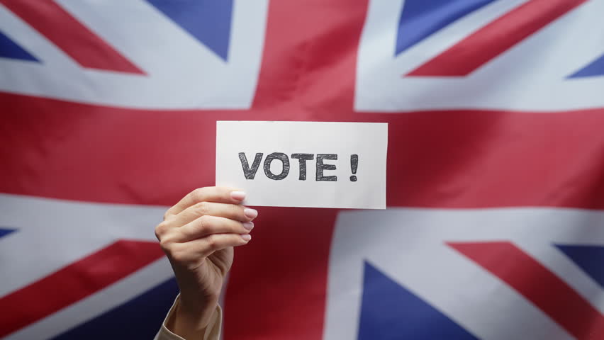 Woman Holds Title Sign With Text Vote, Great Britain Flag Background, General Elections in UK.