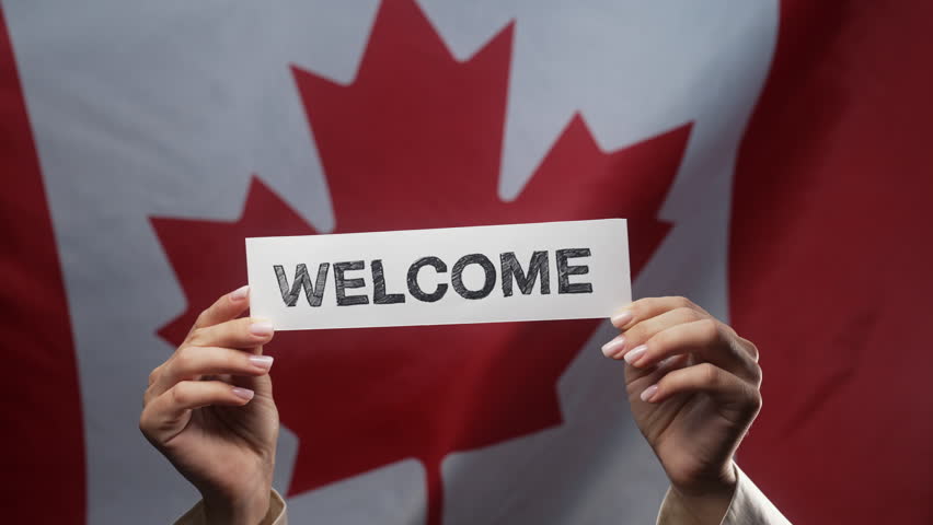 Woman With Welcome Lettering Title Text Cardboard Canadian Flag Backdrop. Canada