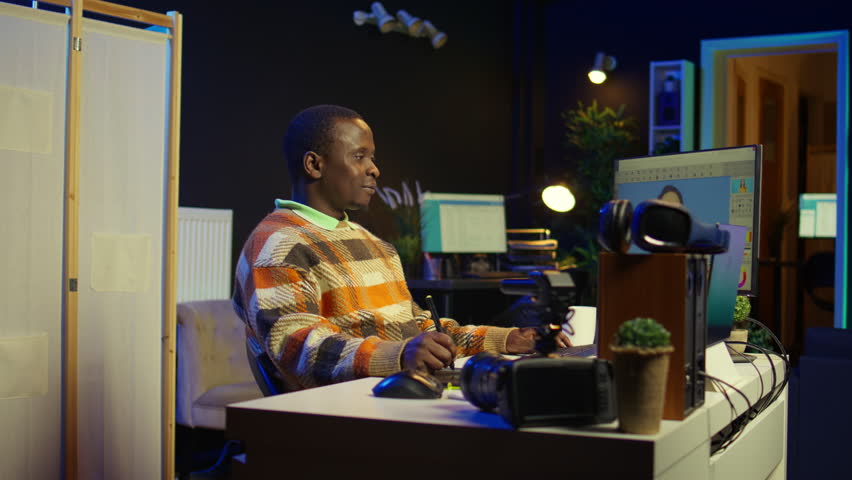 African american male photo editor multitasking on dual monitors in modern setup, illustrating the essentials of remote work and digital design for freelancers. Artistic projects. Camera B.