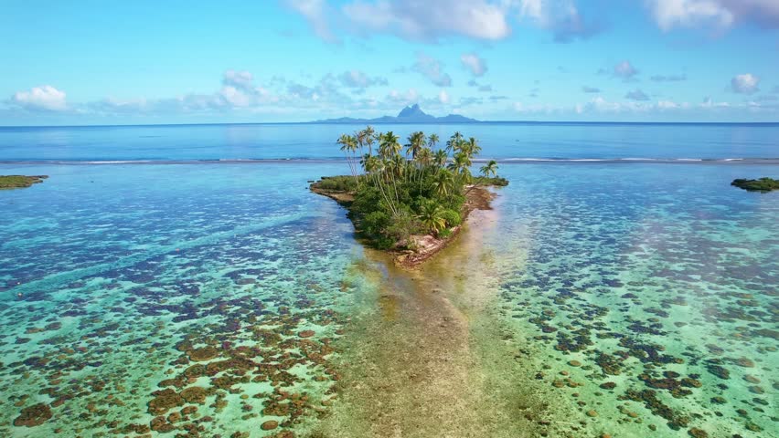 Drone Tahiti. Aerial view of Tahaa island lagoon, tour boat in clear ocean water, Bora Bora island in background. Luxury honeymoon vacation, romantic getaway. tourism destination in French Polynesia. 