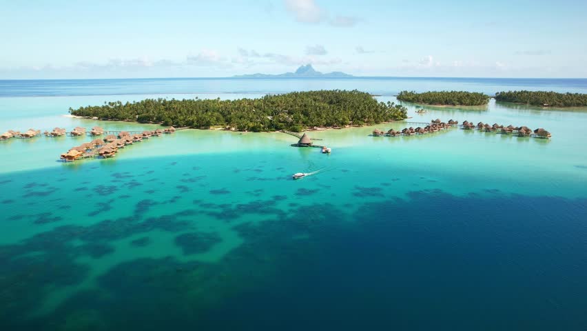 Drone Tahiti. Aerial view of Tahaa island lagoon, tour boat in clear ocean water, Bora Bora island in background. Luxury honeymoon vacation, romantic getaway. tourism destination in French Polynesia. 