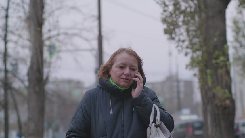 Woman talking on mobile phone in residential area during cloudy evening