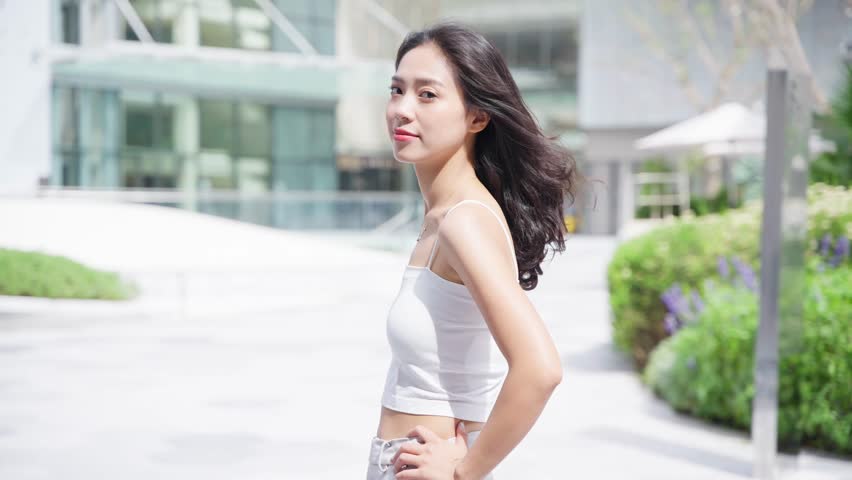 happy attractive young asian woman posing to the camera smile in the sunny summer day at urban street