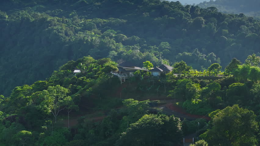 This aerial view shows a picturesque house in the lush forests of Costa Rica, highlighting the beauty of nature and the serene experience of living in such a breathtaking environment