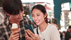 Bonding, night and couple with smartphone, city and smile for live stream, love and vlogger in holiday. Outdoor, eating and influencer with ice cream, fun and Japanese people on vacation and Tokyo - Powered by Shutterstock - Get 15% off with code: PIKWIZARD15