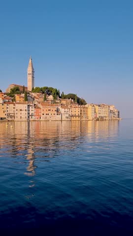 Witness the breathtaking beauty of Rovinj as the golden sun rises over the colorful buildings along the waterfront, casting reflections in the calm Adriatic Sea on a peaceful morning in Croatia