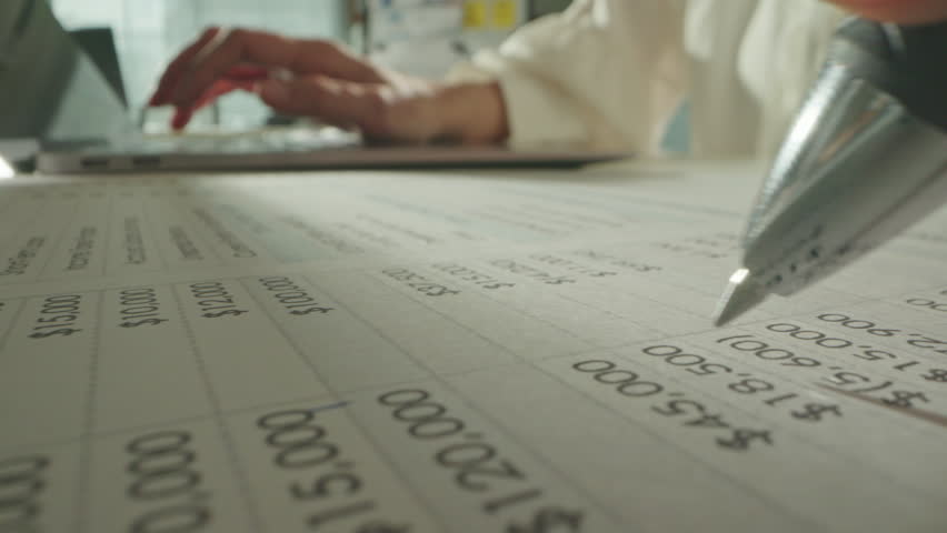 Macro close up of accountant woman working with laptop computer analyzing financial report and data statistics documet in office. Unrecognizable businesswoman checking company balance sheet statement.