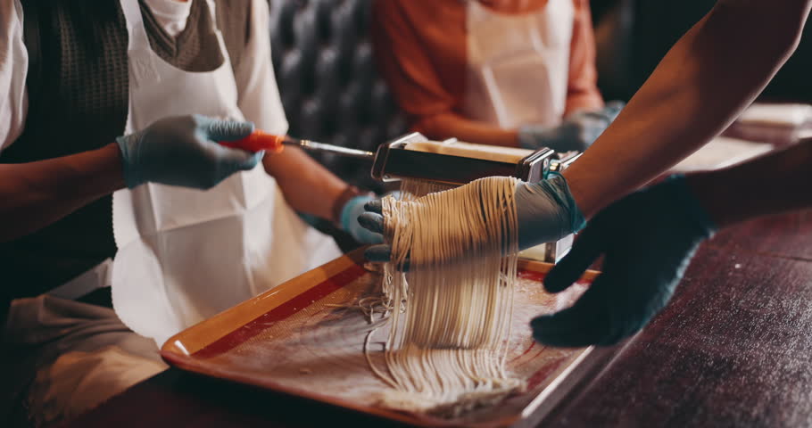 Pasta, machine and people in class for cooking with chef, process and bonding together with Asian food. Cafe, learning and couple making ramen on date with teacher, noodle course and Japanese culture