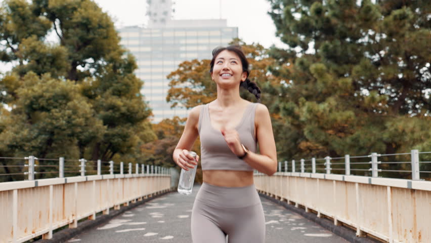 Japanese, running and woman with fitness, cardio and water bottle with wellness. Healthy person, athlete and runner in city, smile or workout with morning routine, exercise or practice with energy