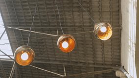 Three industrial-style pendant lights hang from a warehouse ceiling, showcasing stylish lighting design in an urban setting. The bulbs emit a warm glow against the textured ceiling backdrop. - Powered by Shutterstock - Get 15% off with code: PIKWIZARD15