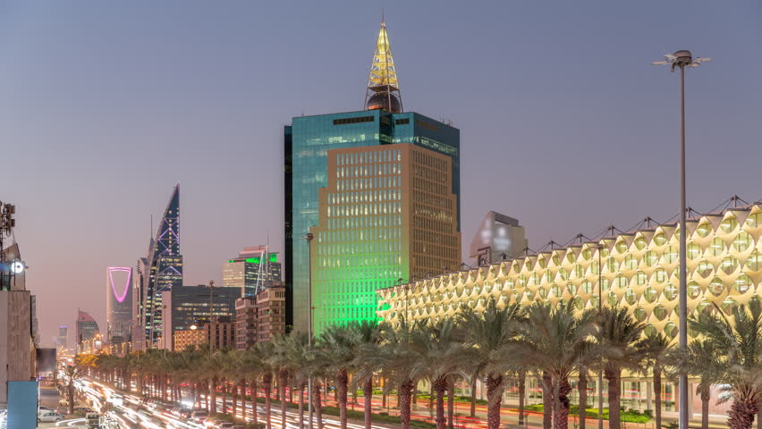 Aerial day to night timelapse of King Fahd Road in Riyadh, Saudi Arabia. Bustling traffic with cars and taxis near the illuminated Riyadh National Library, surrounded by modern towers and skyscrapers