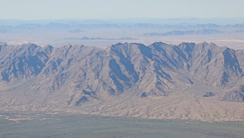A breathtaking aerial view of the rugged Estrella Mountains, showcasing their dramatic peaks and valleys under a clear sky in the Arizona desert landscape.