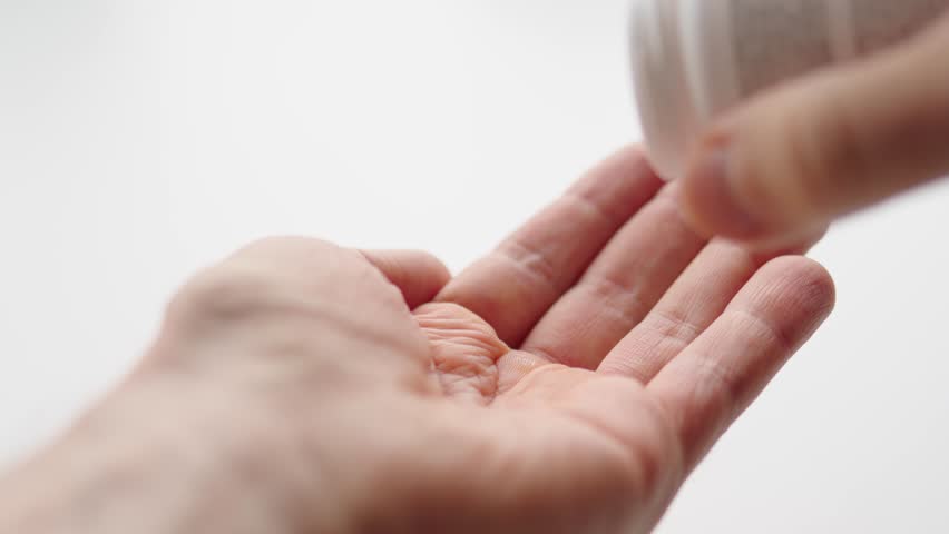 Man pouring vitamin pills on his hand. Vitamin B12. Vegan supplements. Slow motion