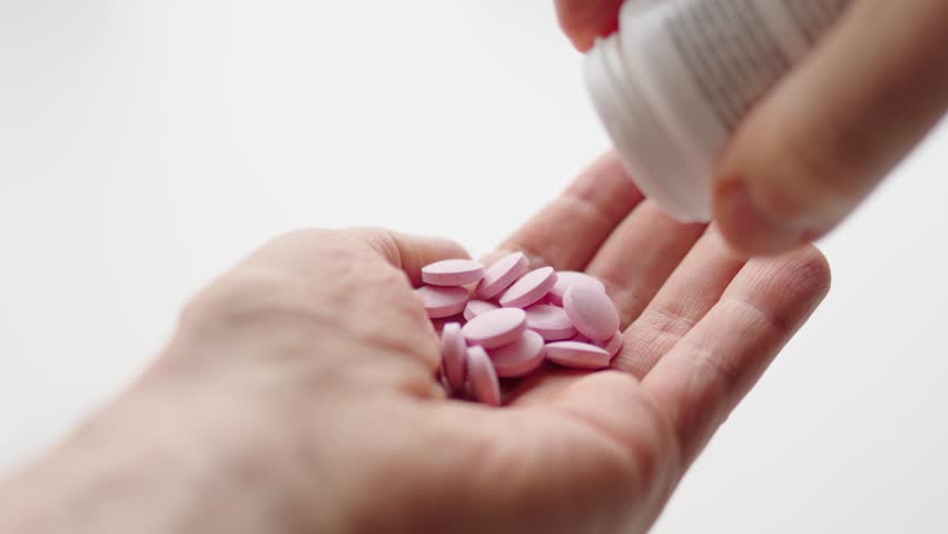 Man pouring vitamin pills on his hand. Vitamin B12. Vegan supplements. Slow motion