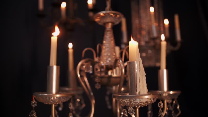 Wax candles burning in a vintage chandelier