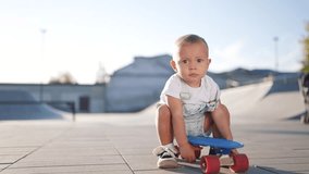 baby rides sitting on a skateboard. happy family kid dream concept. baby son learning to skateboard playing funny video. lifestyle child in a skate park rides a skateboard outdoors - Powered by Shutterstock - Get 15% off with code: PIKWIZARD15