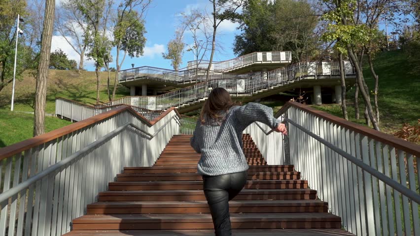 A woman navigates stairs in nature, showcasing vitality and joy
